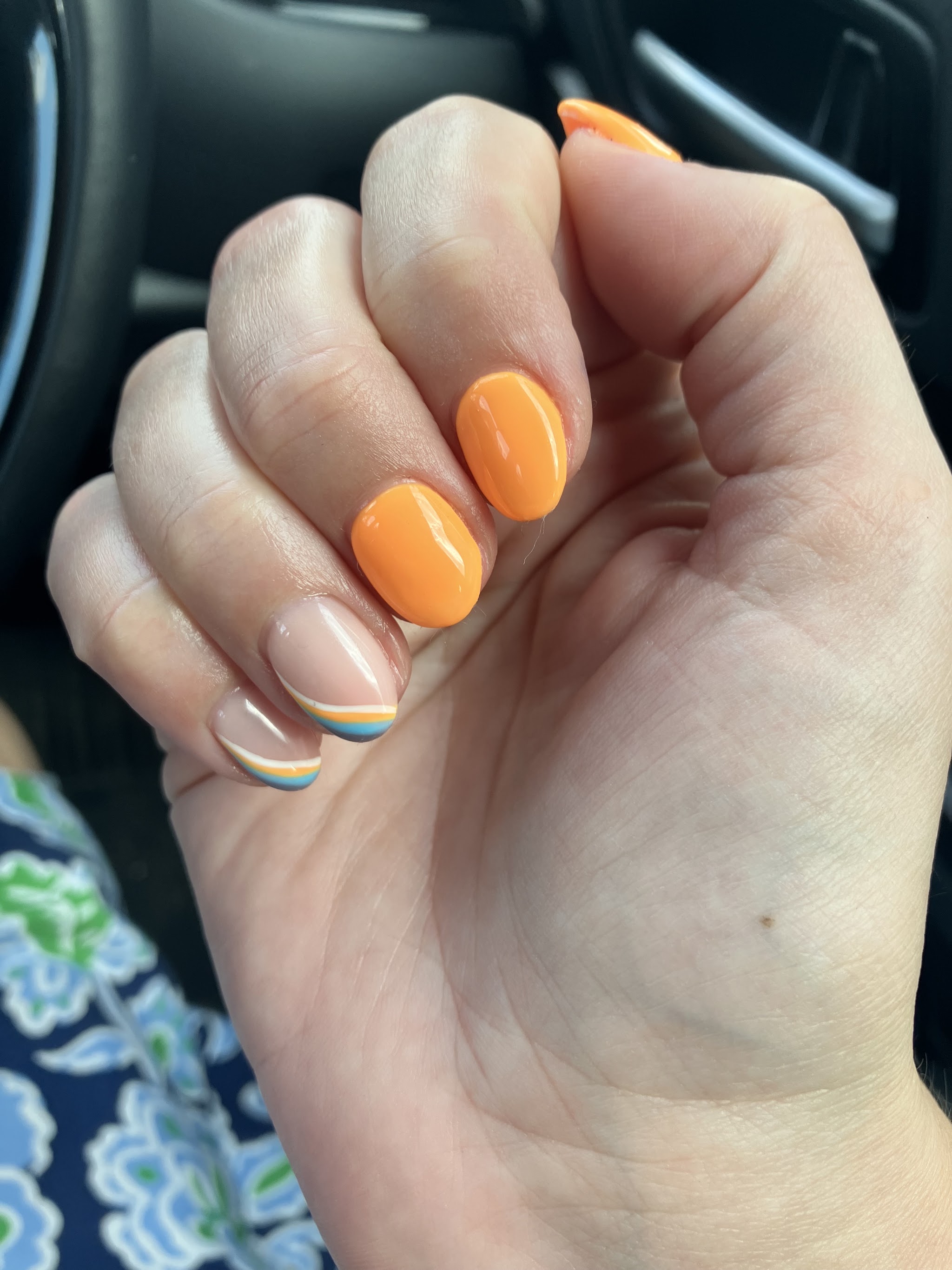 Bright orange manicure with a striped French-tip accent