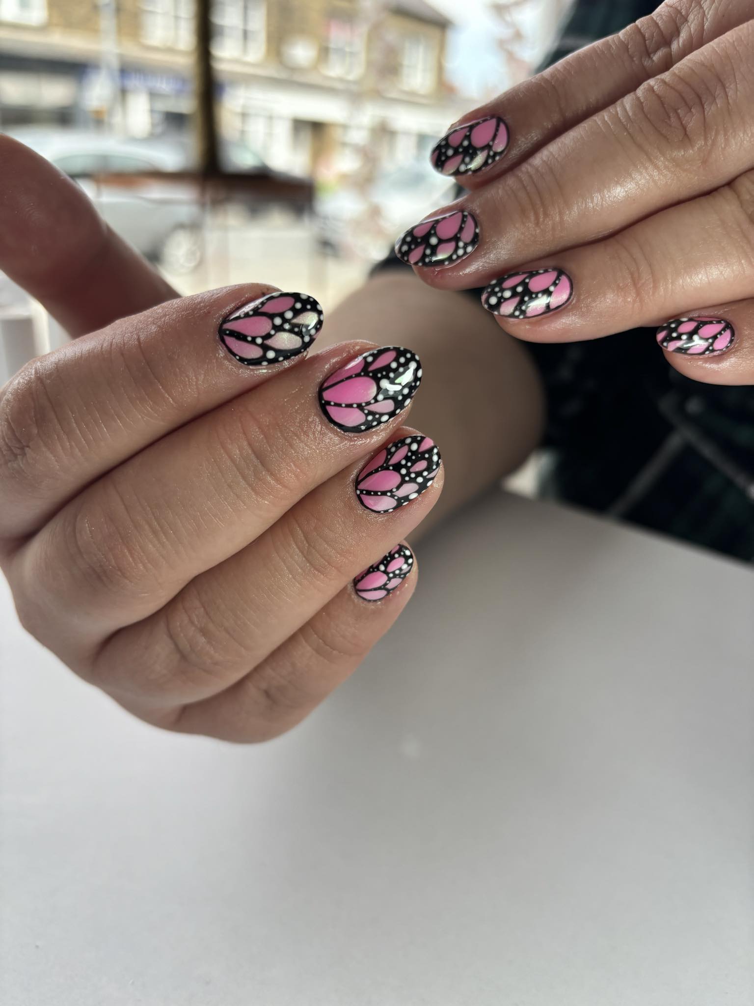Pink and black butterfly-inspired nail art with sparkling details
